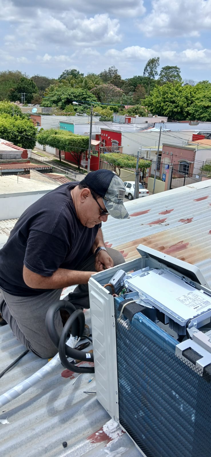 Técnico dando mantenimiento a una unidad de aire acondicionado en techo