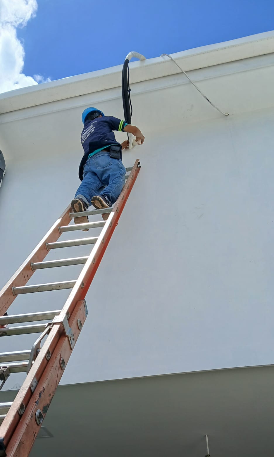 Técnico instalando tubería de refrigeración en fachada